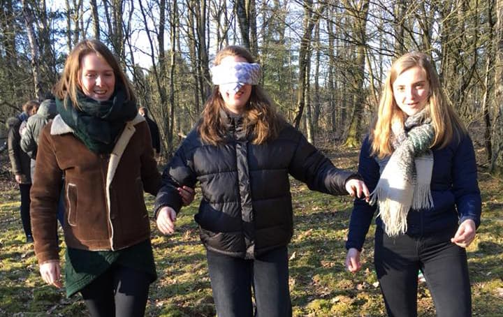 Foto van drie meiden waarvan de middelste een blinddoek op heeft 
